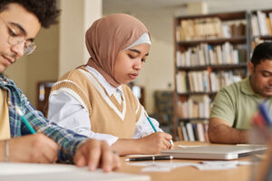 2 Students sitting at a desk, at work on their exams